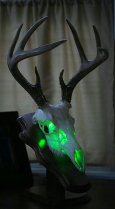 a deer's head with glowing green eyes is shown in front of a window