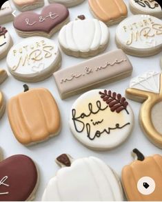 many decorated cookies are displayed on a white tablecloth with writing and pumpkins in the background