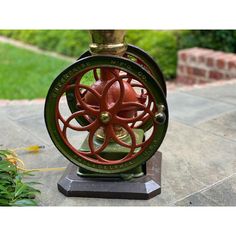 a red and green fire hydrant sitting on top of a cement slab next to grass