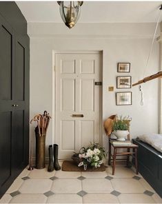 a hallway with white walls and black doors, vases filled with flowers on the floor