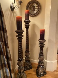 two tall candles sitting next to each other on top of a wooden floor