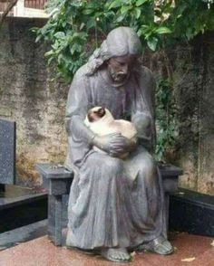 a statue holding a cat sitting on top of a bench