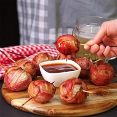 someone is dipping sauce on the skewers with bacon wrapped around them and other appetizers