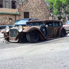 an old car is parked on the side of the road in front of other cars