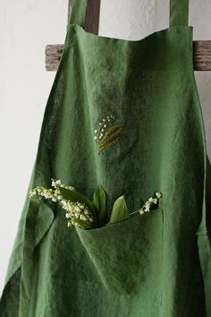 a green apron with flowers in the pocket