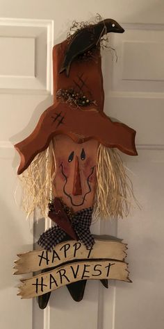 a scarecrow head hanging on the front door with happy harvest ribbon around it's neck