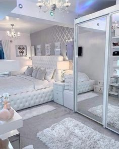 a white bedroom with mirrored walls and chandelier hanging from the ceiling, along with carpeted flooring