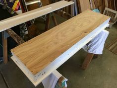 a wooden bench sitting on top of a hard wood floor next to a pile of plywood