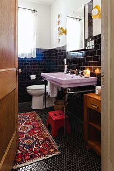 the bathroom is decorated in black and white with red accents, including a pink sink