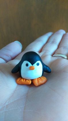 a small toy penguin sitting on the palm of someone's hand