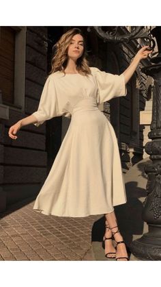 a woman in a white dress standing next to a lamp post