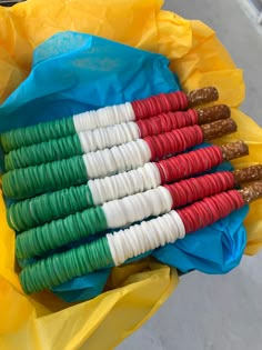 a bunch of food wrapped in plastic on top of a yellow wrapper with red, white and green rings