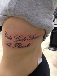 a woman with a tattoo on her stomach that says, under god's arms be fearless