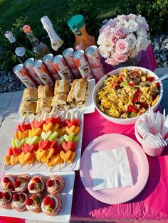 a table topped with food and drinks on top of a pink cloth covered tablecloth