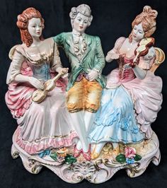 three figurines sitting on top of a table next to each other, one holding a guitar