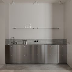 an empty kitchen with stainless steel cabinets and counter tops, along with shelves above the sink