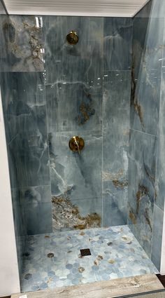 a shower with blue and gold tiles on the walls