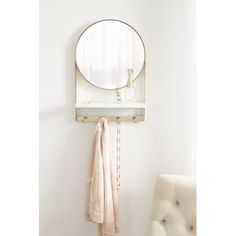 a white chair sitting next to a round mirror on a wall above a towel rack