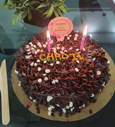 a chocolate birthday cake with lit candles on top