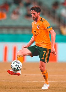 a man kicking a soccer ball on top of a field