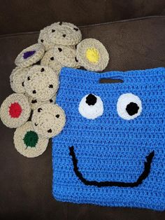 a blue crocheted bag with eyes and mouth sitting next to some stuffed teddy bears