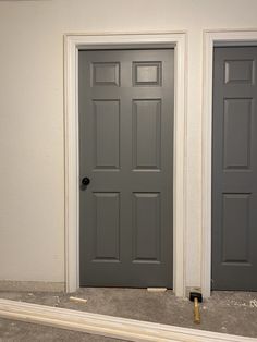 two gray doors are in the corner of a room with no carpeting on the floor