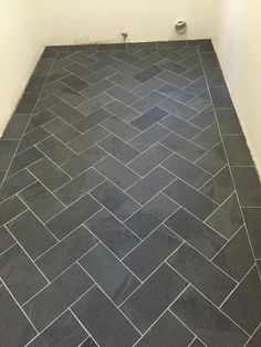 a bathroom with a black tile floor and white walls, along with a toilet in the corner