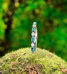 a stack of rings sitting on top of a moss covered rock