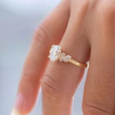 a woman's hand with a diamond ring on top of her finger and the other hand holding it