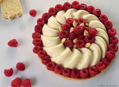 a dessert with raspberries and cream frosting on a white surface next to some crackers