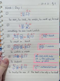 a hand holding up a notebook with writing on it and korean characters in the background