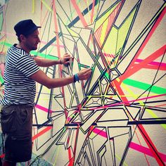 a man drawing on a wall with colorful lines