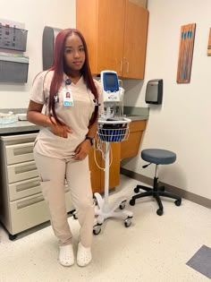 a woman in white scrubs standing next to a medical equipment stand with her hands on her hips