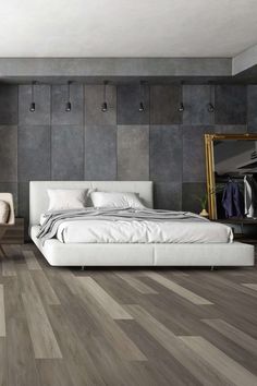 a bedroom with grey walls and wooden floors, white furniture and a large mirror on the wall