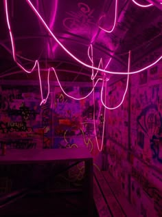 neon lights hang from the ceiling in a room with graffiti covered walls and purple lighting