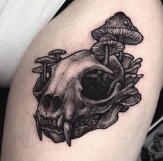 a black and white photo of a skull with mushrooms on it's side thigh