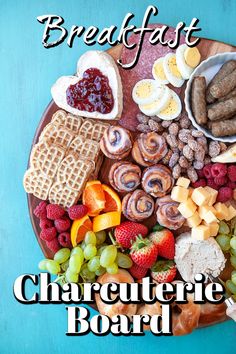 a platter filled with different types of food on a blue tablecloth, including fruit, sausages and waffles