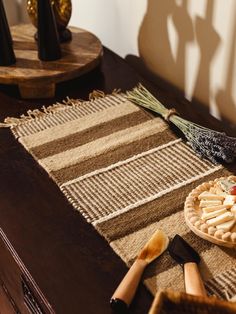 Beige and brown striped woven table runner displayed on a dark wooden sideboard, decorated with lavender, a cheese platter, and wooden spreaders. African Weaving, Woven Table Runner, Best Travel Accessories, Hot Dishes, Local Produce, Gifts For Teachers, Framed Gifts, Wool Scarf, Rio Grande