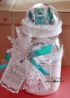 there is a glass jar that has snowflakes in it and a tag on the lid