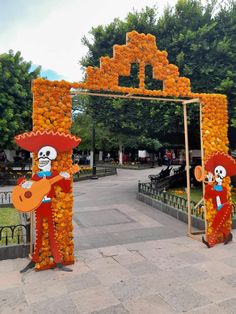 an outdoor area decorated with orange flowers and skeleton figures, including a man playing the guitar