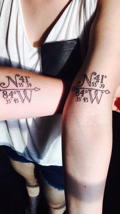 two people with matching tattoos on their arms, one has an arrow and the other has numbers