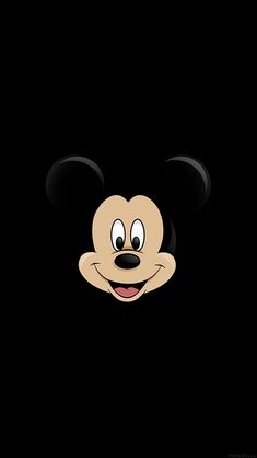 a mickey mouse face in the dark with its eyes open and tongue sticking out from it's mouth