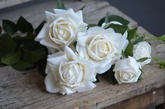 some white roses are sitting on a wooden table