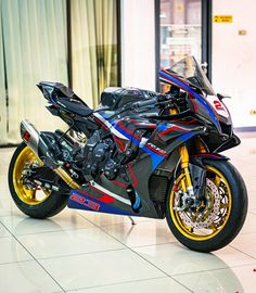 a motorcycle is parked in front of a building with its lights on and it's red, white, and blue paint scheme