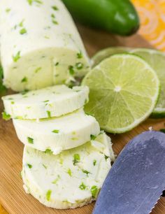 sliced limes on a cutting board next to a knife and some cut up cheese