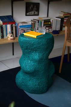 there is a blue stool that looks like a snowman in the living room with bookshelves behind it