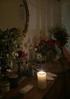 a candle is lit on a table with flowers in vases and other items around it