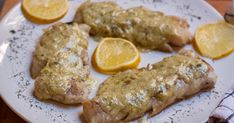 three pieces of fish on a plate with lemons