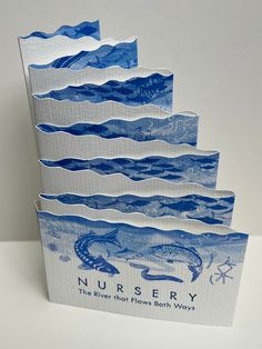 three blue and white greeting cards with the words nursery on them, stacked up against each other