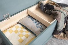 an open drawer with some pillows and blankets in it